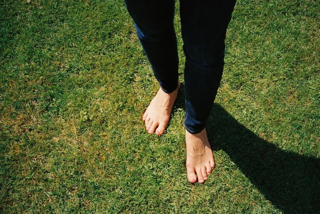 Berjalan tanpa alas kaki di atas rumput untuk grounding earthing