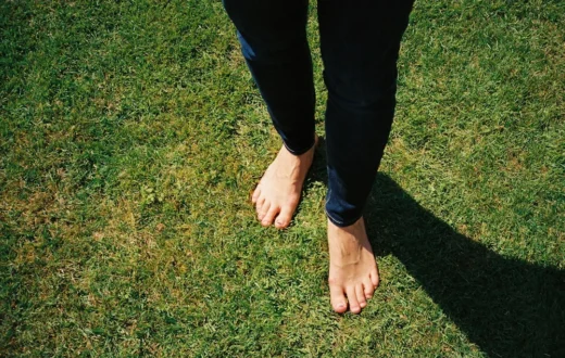 Berjalan tanpa alas kaki di atas rumput untuk grounding earthing