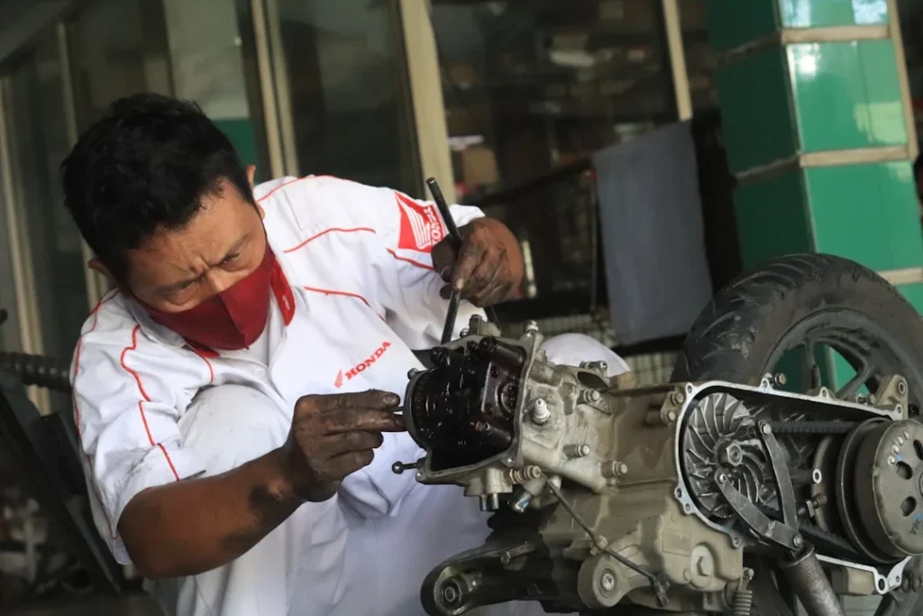 Mekanik sedang mengecek komponen mesin saat motor injeksi sering mati mendadak